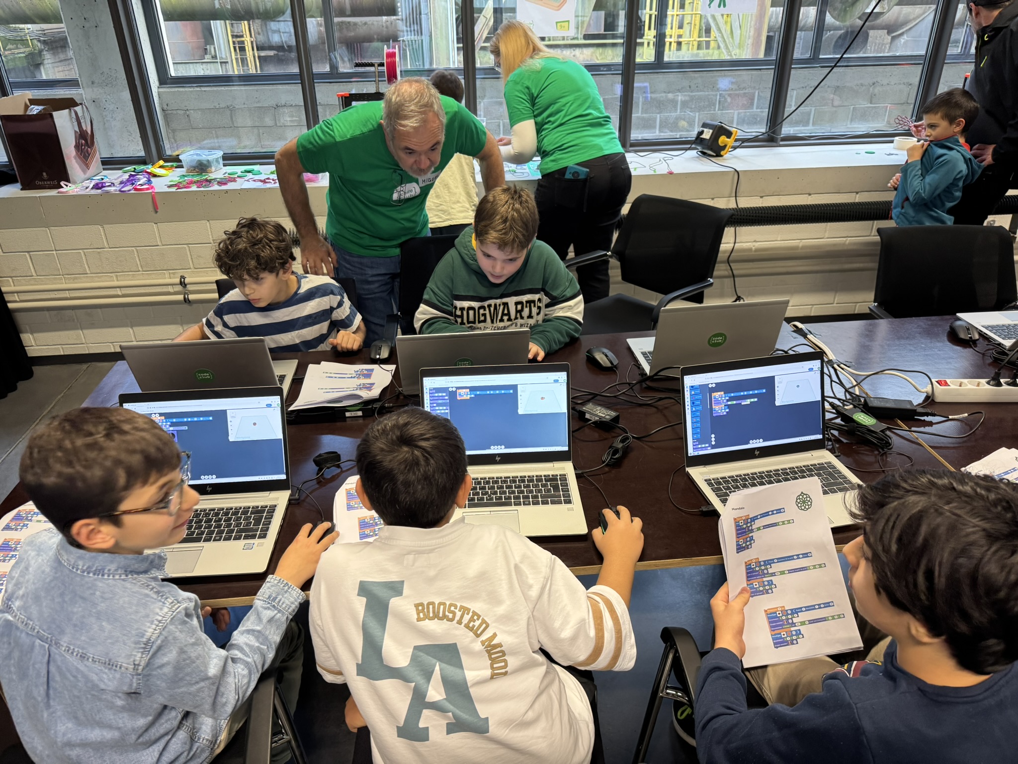 Jeune concentré devant son écran pendant une séance de code, accompagné d’un coach